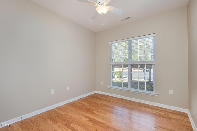 spare room with light wood finished floors, a ceiling fan, visible vents, and baseboards