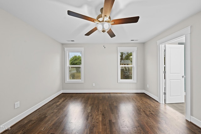 empty room with visible vents, dark wood-style flooring, and a wealth of natural light