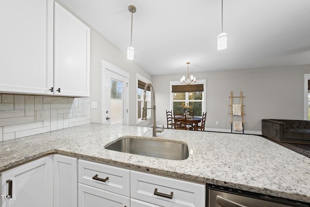 kitchen with light stone counters, backsplash, white cabinets, a sink, and dishwasher