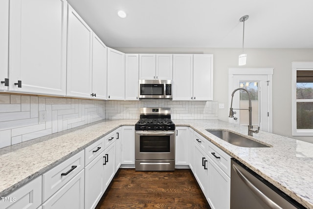 kitchen with decorative backsplash, white cabinets, dark wood-style floors, appliances with stainless steel finishes, and a sink