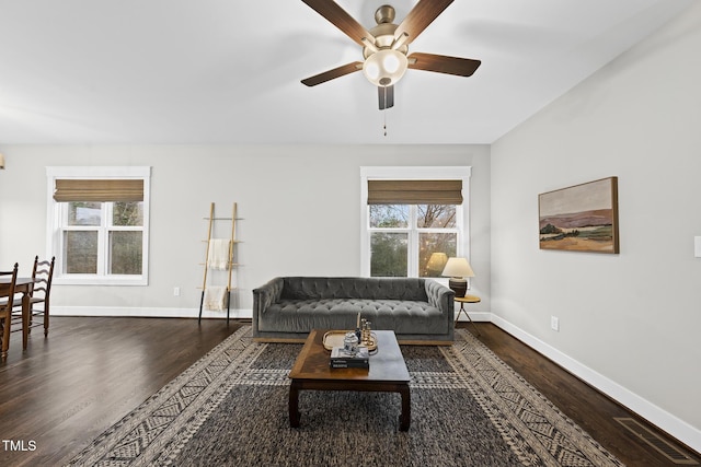 living area with dark wood-style floors, plenty of natural light, baseboards, and a ceiling fan