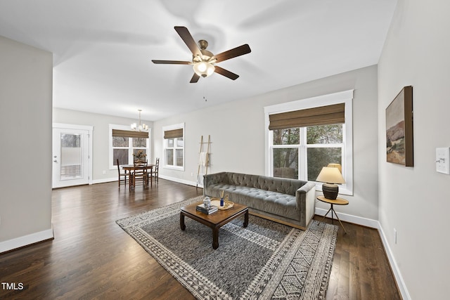 living room with dark wood finished floors, baseboards, and ceiling fan with notable chandelier