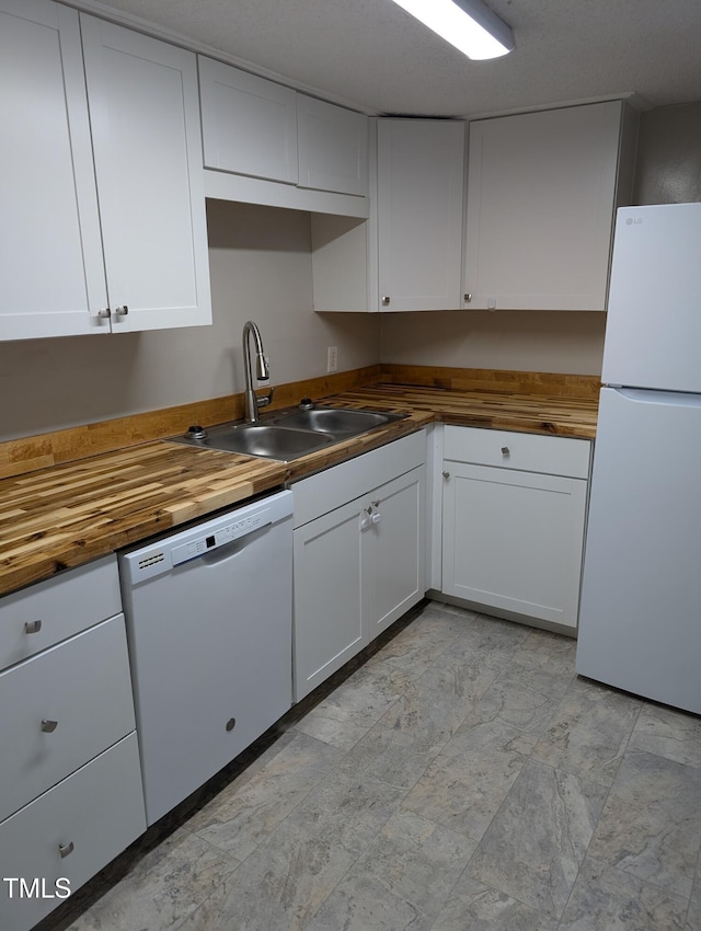 kitchen featuring white appliances, butcher block counters, white cabinets, and a sink