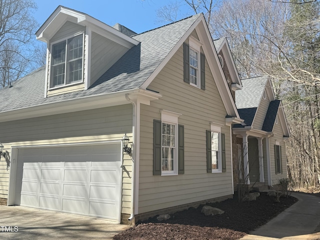 view of side of home featuring concrete driveway, roof with shingles, and an attached garage