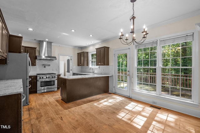 kitchen with stainless steel appliances, visible vents, dark brown cabinetry, a peninsula, and wall chimney exhaust hood