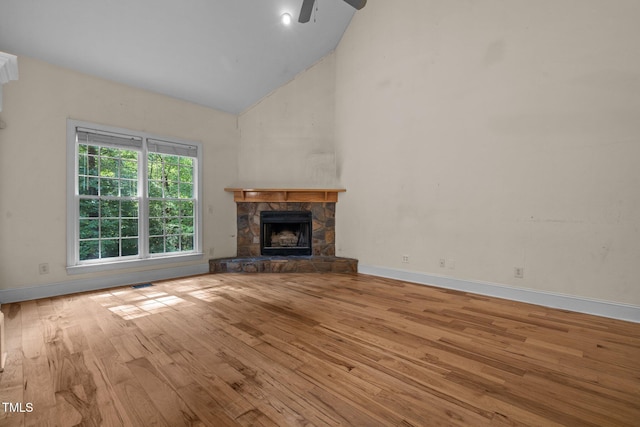 unfurnished living room with high vaulted ceiling, a fireplace, baseboards, and wood finished floors