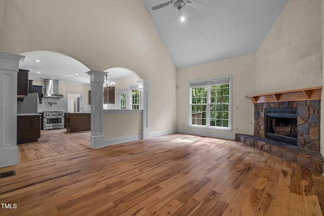 unfurnished living room featuring light wood finished floors, visible vents, ceiling fan, a fireplace, and high vaulted ceiling