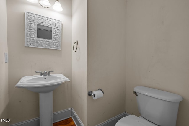 bathroom featuring baseboards, a sink, and toilet