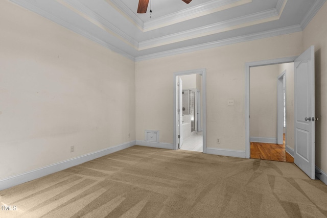 unfurnished bedroom with a raised ceiling, light carpet, and crown molding