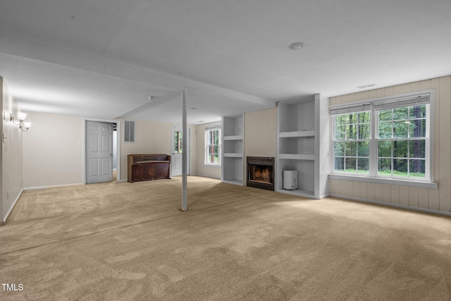 unfurnished living room featuring carpet floors, a fireplace, visible vents, and built in features