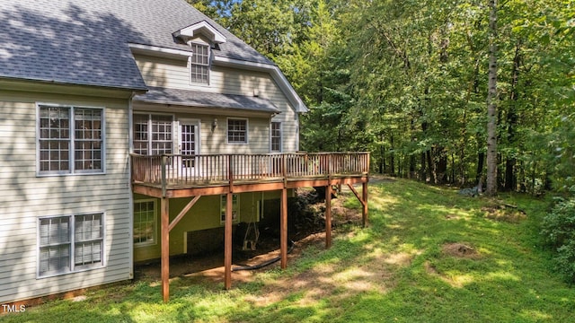 rear view of house with a yard, a shingled roof, and a wooden deck