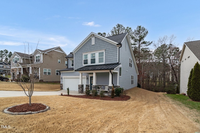 view of front facade featuring metal roof, a porch, an attached garage, concrete driveway, and a standing seam roof