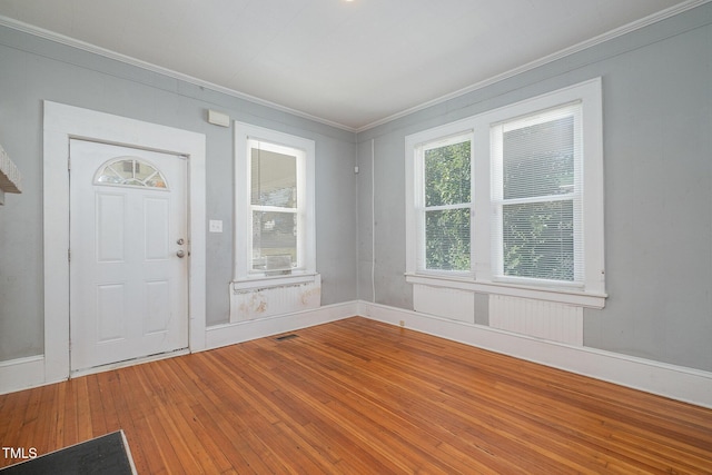 foyer entrance with crown molding, visible vents, and hardwood / wood-style floors