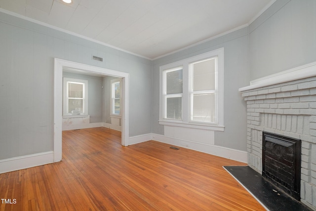 unfurnished living room featuring a brick fireplace, wood-type flooring, visible vents, and crown molding