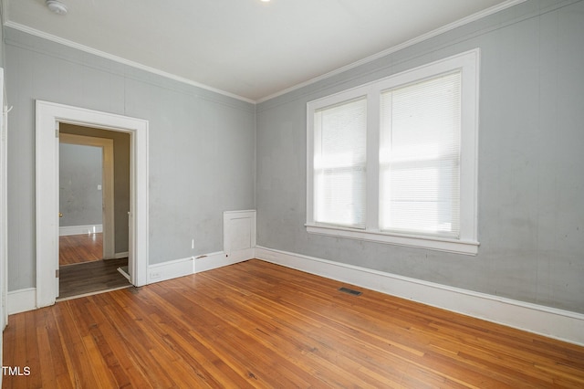 spare room with baseboards, visible vents, crown molding, and hardwood / wood-style floors