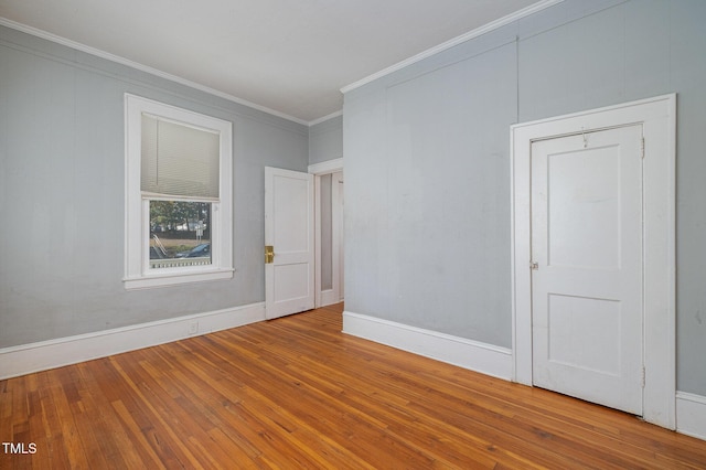 empty room featuring ornamental molding, baseboards, and hardwood / wood-style floors