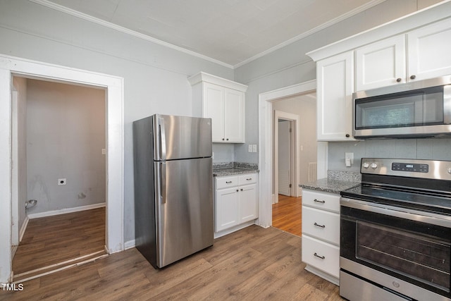 kitchen featuring crown molding, wood finished floors, appliances with stainless steel finishes, white cabinetry, and light stone countertops