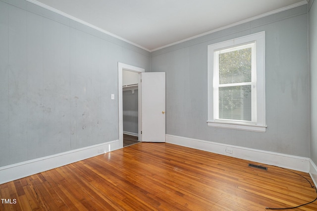 unfurnished room featuring ornamental molding, visible vents, baseboards, and hardwood / wood-style flooring