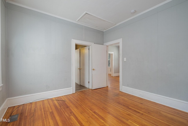 empty room featuring visible vents, hardwood / wood-style flooring, attic access, and baseboards