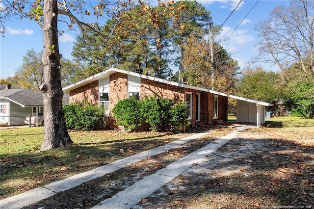 view of front facade with driveway, brick siding, and a front yard