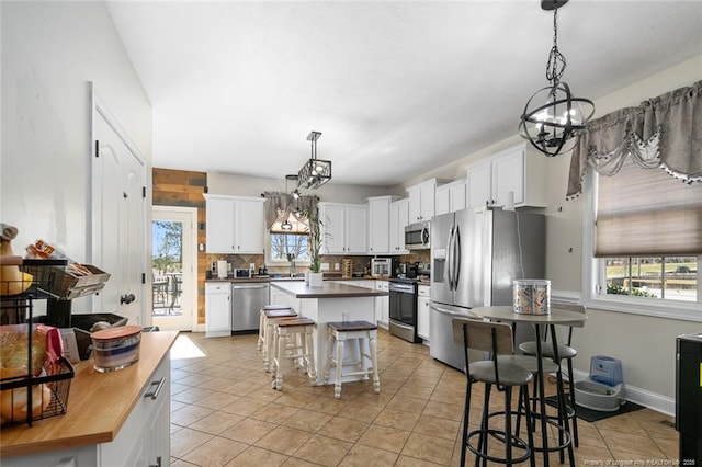 kitchen featuring tasteful backsplash, butcher block counters, appliances with stainless steel finishes, white cabinets, and a kitchen island