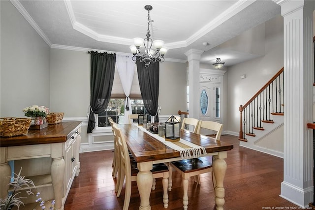 dining room with dark wood-type flooring, a tray ceiling, and decorative columns