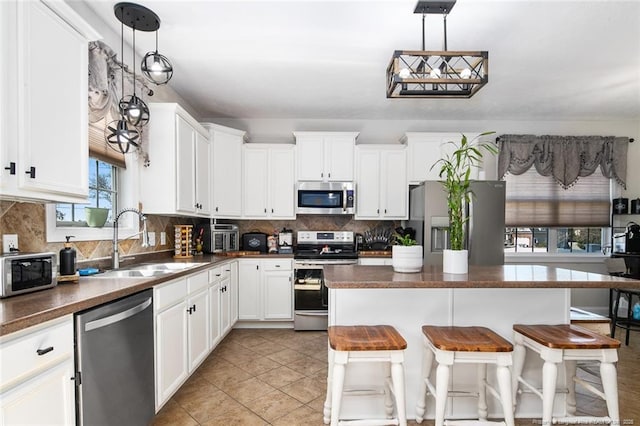 kitchen featuring appliances with stainless steel finishes, backsplash, dark countertops, and a sink