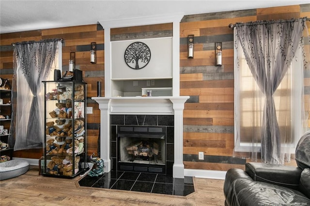 living room featuring a fireplace, wooden walls, and wood finished floors