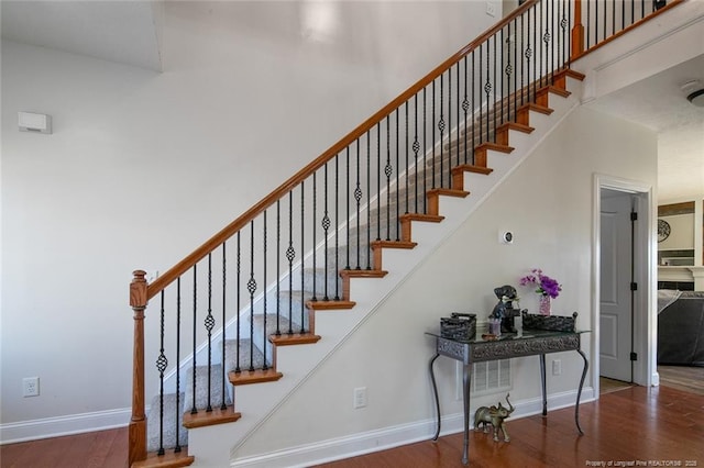 stairs featuring baseboards, a high ceiling, and wood finished floors