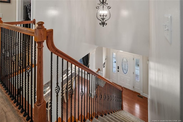 entrance foyer with a towering ceiling, wood-type flooring, and a chandelier