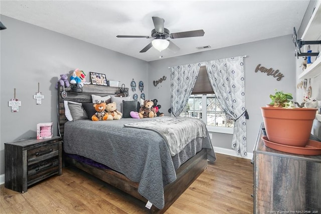 bedroom with ceiling fan, wood finished floors, visible vents, and baseboards