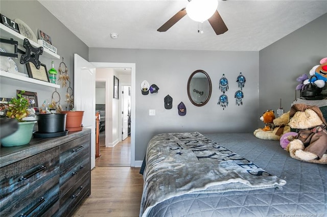 bedroom with a ceiling fan, baseboards, and wood finished floors