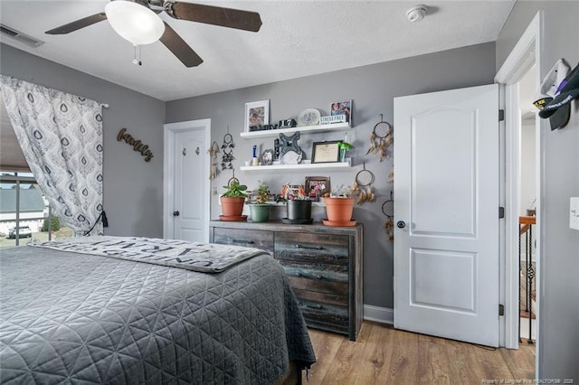 bedroom with light wood-type flooring, baseboards, visible vents, and a ceiling fan