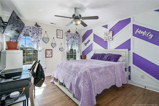 bedroom with visible vents, ceiling fan, baseboards, and wood finished floors