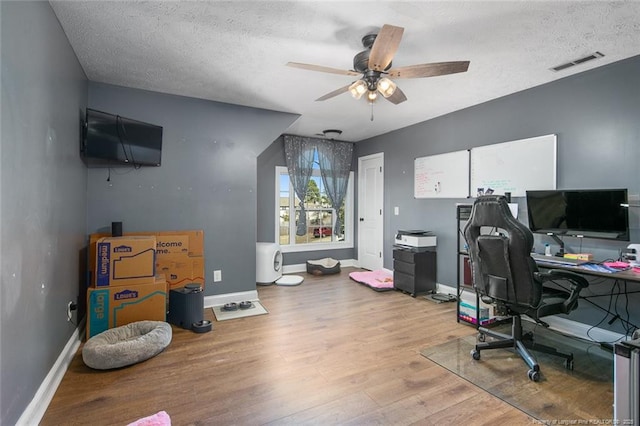 office area with baseboards, visible vents, ceiling fan, and light wood finished floors