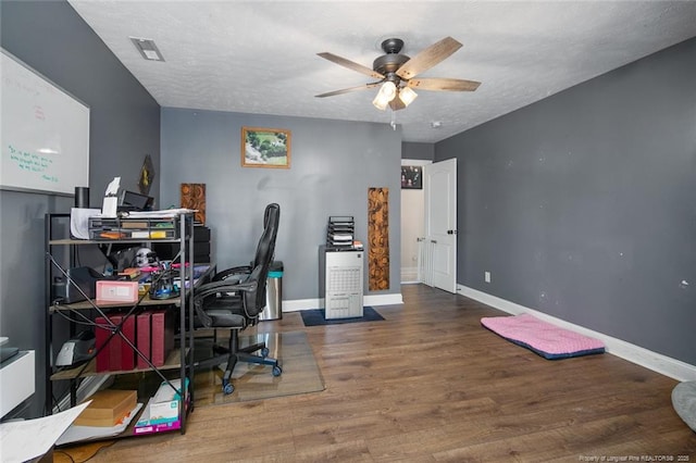 home office with a textured ceiling, ceiling fan, wood finished floors, and baseboards