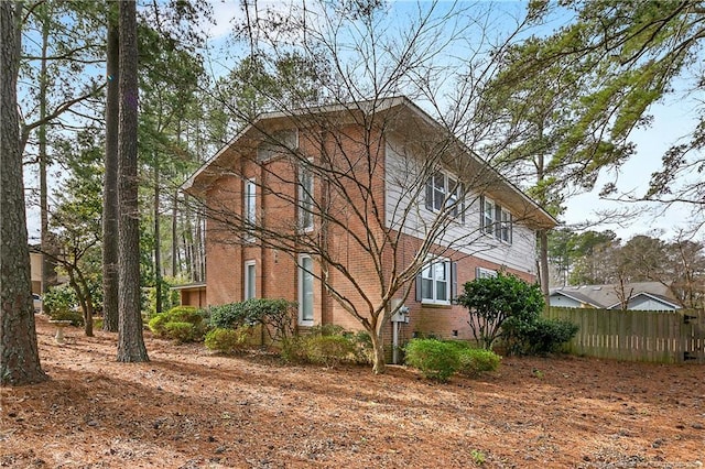 view of home's exterior with crawl space, fence, and brick siding