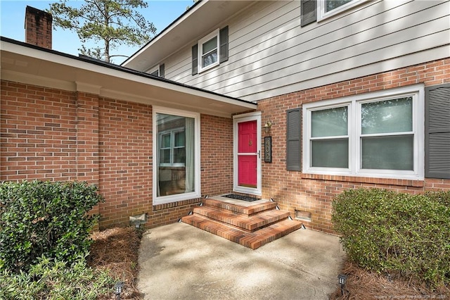 property entrance featuring crawl space and brick siding