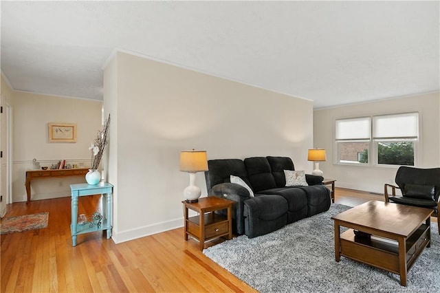 living room featuring light wood-type flooring, baseboards, and crown molding