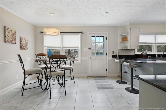 dining area with light tile patterned floors, baseboards, and a textured ceiling