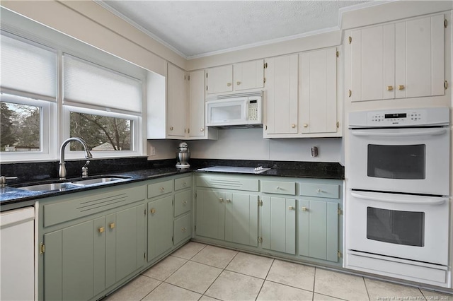 kitchen featuring light tile patterned floors, a textured ceiling, white appliances, a sink, and crown molding