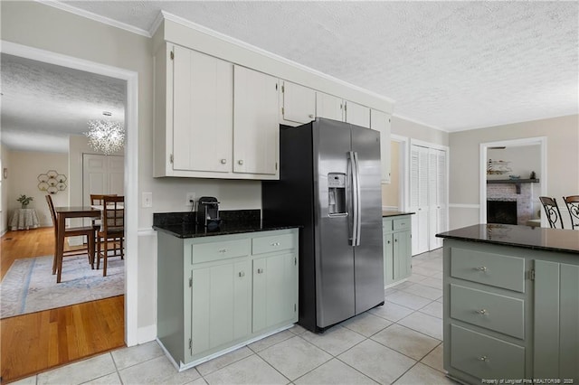 kitchen featuring a textured ceiling, light tile patterned flooring, a fireplace, white cabinetry, and stainless steel fridge