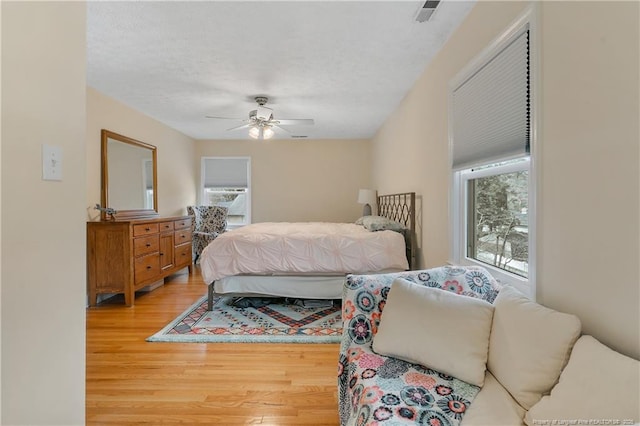 bedroom featuring a textured ceiling, ceiling fan, light wood-type flooring, and visible vents