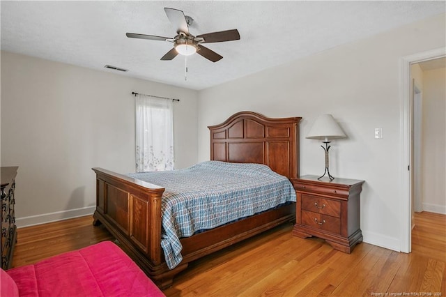 bedroom featuring light wood-style floors, baseboards, visible vents, and ceiling fan