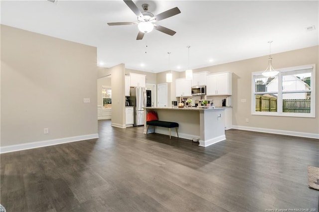 kitchen featuring baseboards, white cabinets, appliances with stainless steel finishes, open floor plan, and dark wood-style flooring