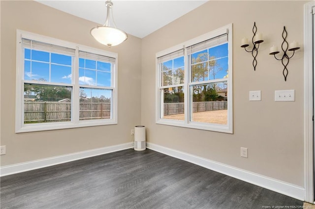 unfurnished room with a healthy amount of sunlight, baseboards, and dark wood-type flooring