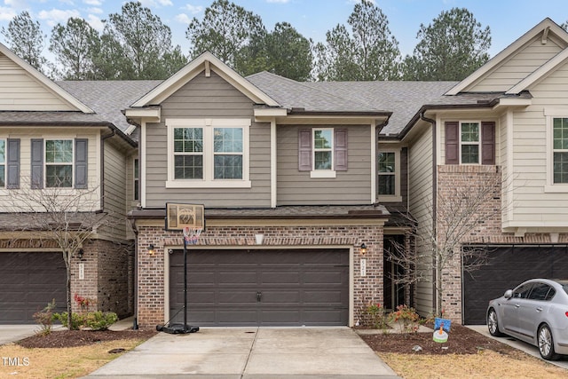 view of property featuring driveway, brick siding, roof with shingles, and an attached garage