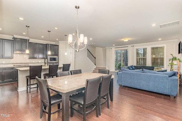 dining room with a notable chandelier, visible vents, stairs, ornamental molding, and dark wood-style floors