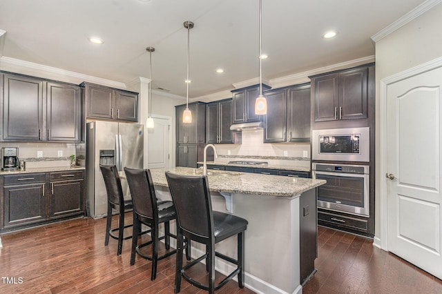 kitchen with appliances with stainless steel finishes, dark wood-type flooring, ornamental molding, a sink, and light stone countertops