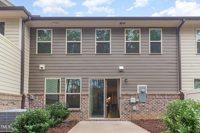 back of property with a patio area, brick siding, and central air condition unit